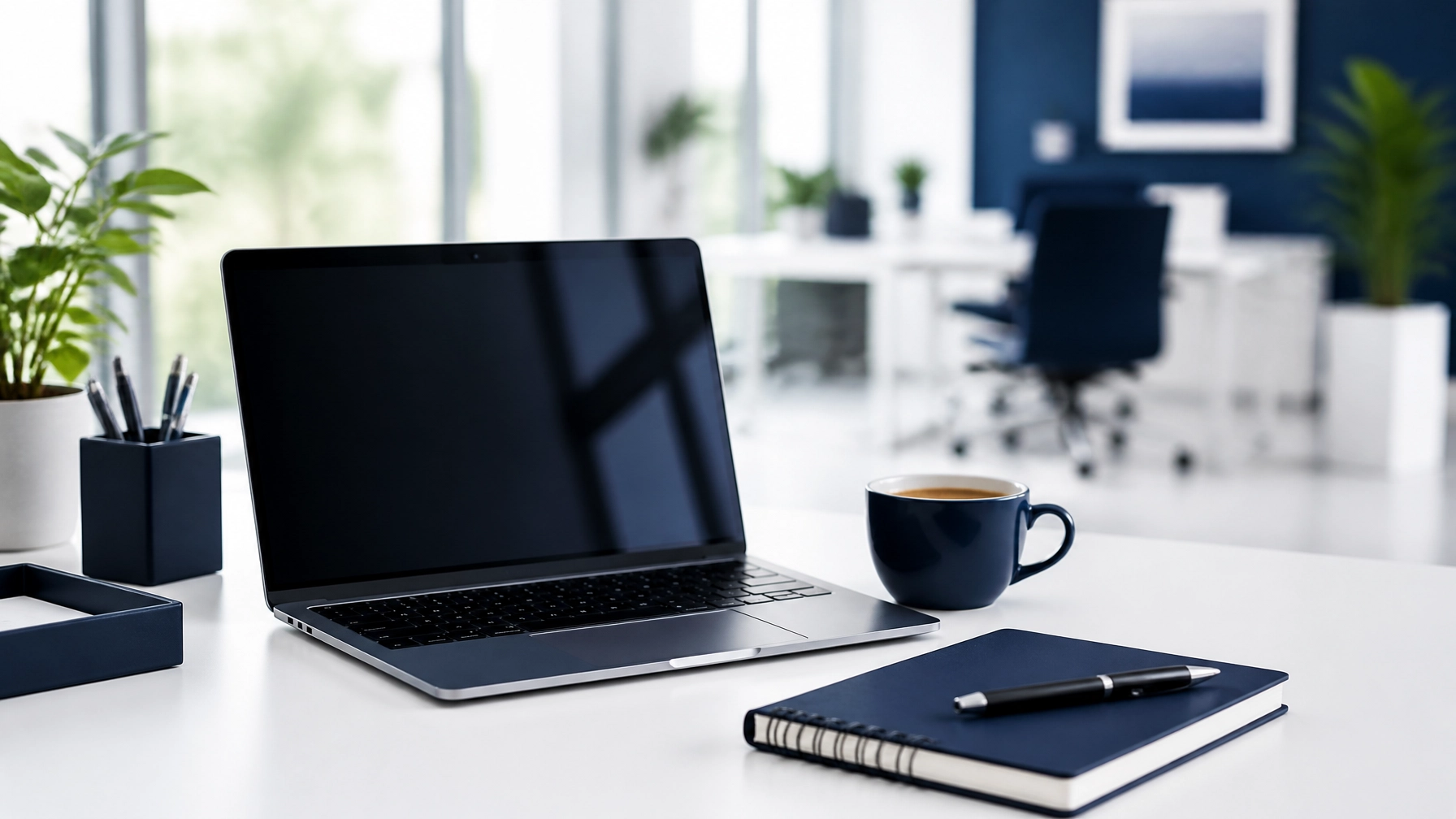 A bright, modern workspace with a laptop, a notebook, and a cup of coffee on a white desk.
