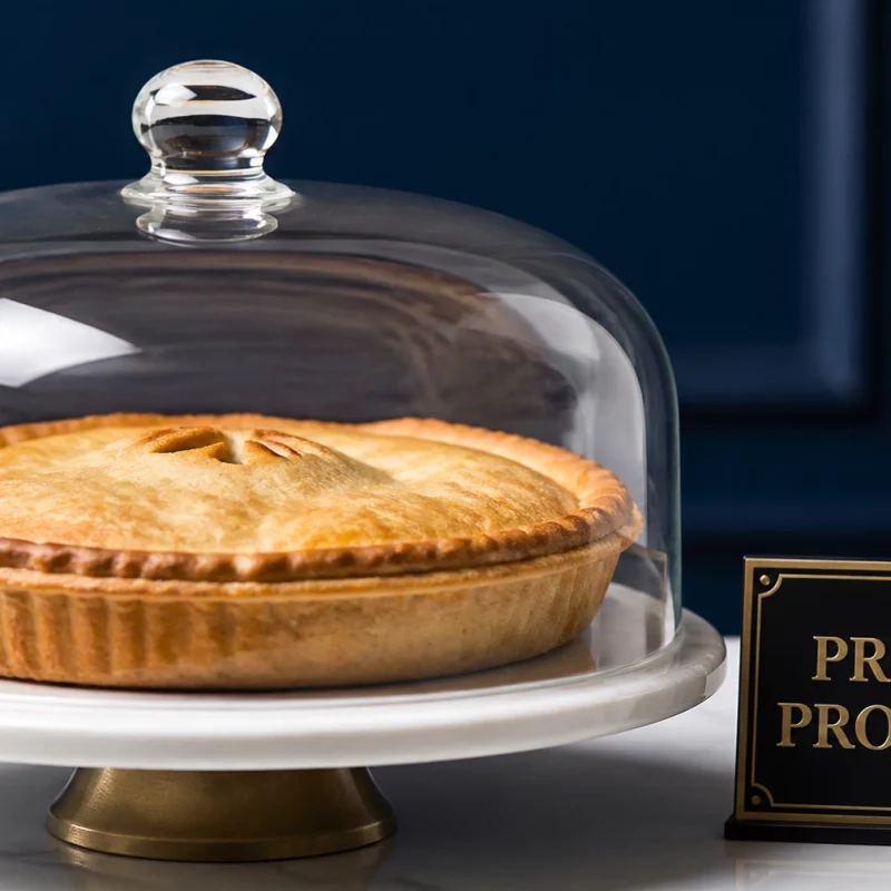 Pie displayed under a glass cloche on a white pedestal, with a dark blue background and a 'PRIVATE PROPERTY' sign nearby.